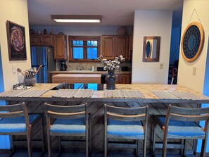 A kitchen with wooden cabinets, a large window, a dining table with chairs, and a vase with flowers. - Serene 3-bedroom townhome in Crested Butte perfect for getaway (Crested Butte)