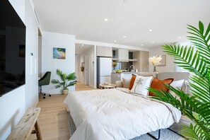 A modern bedroom with a large bed, a desk, and a kitchenette in the background. - Ocean Views at Yves Mermaid Beach (Mermaid Beach)