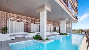 A modern hotel pool area with a clear blue pool, white lounge chairs, and a geometric patterned wall. - Ocean Views at Yves Mermaid Beach (Mermaid Beach)