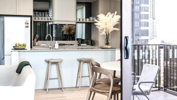 A modern kitchen with a central island, bar stools, and a dining table. - Ocean Views at Yves Mermaid Beach (Mermaid Beach)