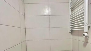 A small, tiled bathroom with a toilet and a hand dryer. - Golders Green Cozy City Studio in London (London)