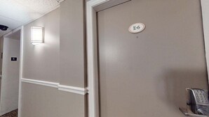 A hotel corridor with a door labeled "E-6" and a phone on a stand. - Mt Green 2-e06 (Killington)