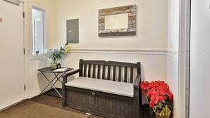 A hallway with a bench, a small table with a vase of flowers, and a wall-mounted mirror. - Hotel Style Condo Promising a Comfortable and Convenient Retreat Right in the Heart of Vermont ski Country (Killington)