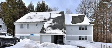 A two-story house with a snow-covered roof and a garage door.