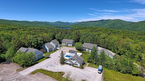 An aerial view of a residential area with houses, a swimming pool, and a mountain backdrop. - Killington Center 531 (Killington)