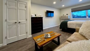 A modern bedroom with a bed, a TV, a dresser, and a window with a view. - Killington Center 531 (Killington)