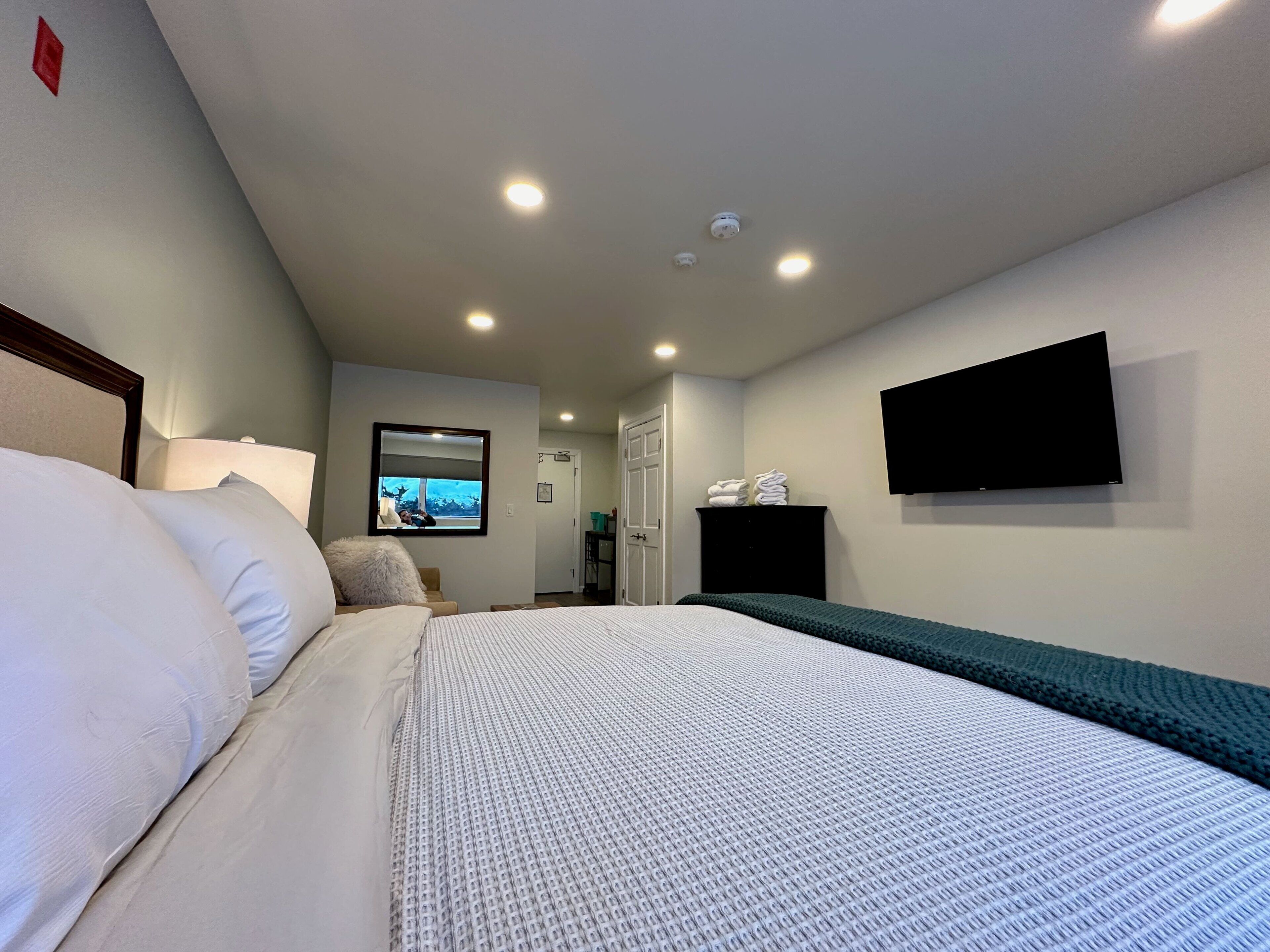 Une chambre d’hôtel avec un lit, un téléviseur fixé au mur et une porte donnant accès à la salle de bain.
