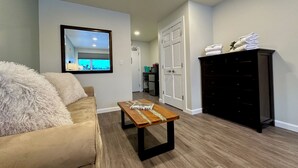 A living room with a beige sofa, a wooden coffee table, a dark wooden dresser, and a white door. - Killington Center 531 (Killington)
