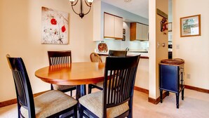 A dining area with a round wooden table and four chairs, a chandelier, and artwork on the walls. - Sunrise - W Glade J-1 (Killington)