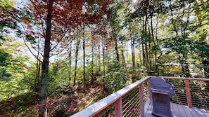 A wooden deck with a railing overlooking a forested area with trees and a clear sky. - Great Escape Ski Lodge (Killington)