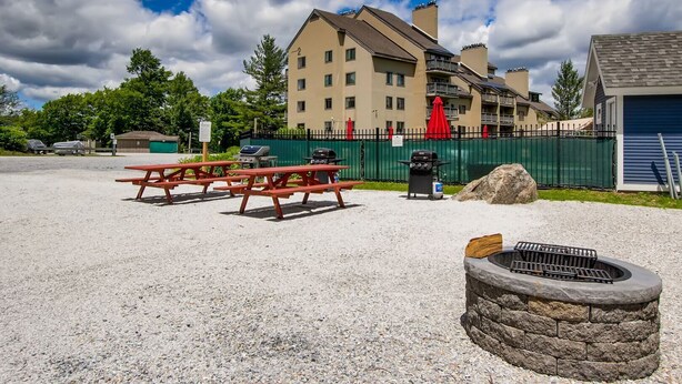 A gravel parking area with picnic tables and a stone fire pit.
