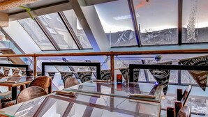 A restaurant with a high ceiling and skylights, featuring a glass table and chairs, and framed pictures of Jack Daniel's whiskey.