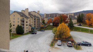 A residential area with multi-story apartment buildings, a parking lot, and autumn foliage.