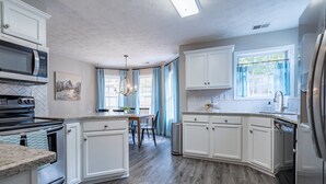 Une cuisine moderne avec des meubles blancs, un plan de travail en granit, un réfrigérateur en acier inoxydable et un four encastré.