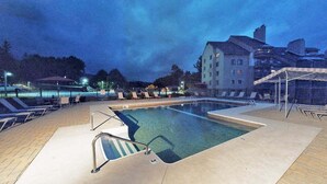 A swimming pool with sun loungers and a building in the background.