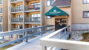 A multi-story building with balconies, a wooden deck, and a sign for Mountain Green Resort.