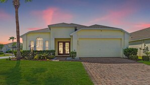A single-story house with a front garage, a well-maintained lawn, and a brick driveway. - NEW King Bed Glow In The Dark Kid Cave (Kissimmee)