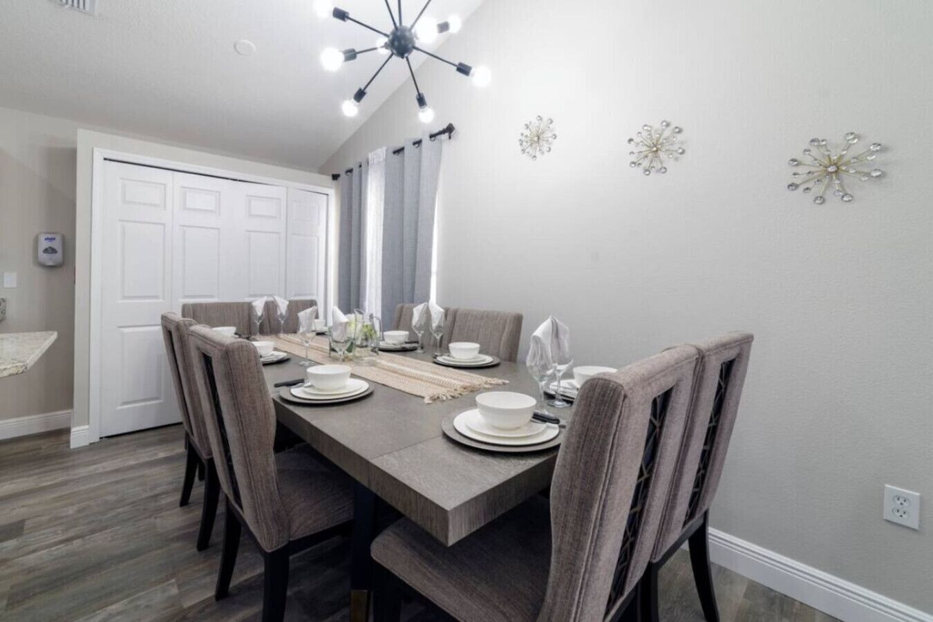 A dining room with a rectangular table set for six, surrounded by six chairs.