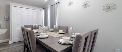 A dining room with a rectangular table set for six, surrounded by six chairs.