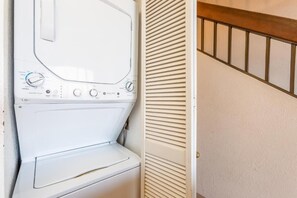 En tvättmaskin med frontmatning i ett tvättrum med en trätrappa och en vit vägg.
