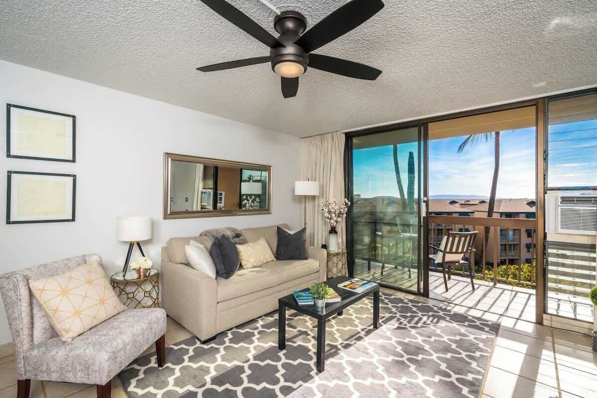 A modern living room with a ceiling fan, a sofa, a chair, a coffee table, and a large sliding glass door leading to a balcony.