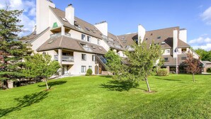Un edificio residencial de varios pisos con un césped cuidado y árboles.