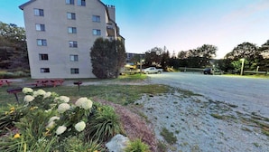 Un edificio de varios pisos con estacionamiento y mesas de picnic.