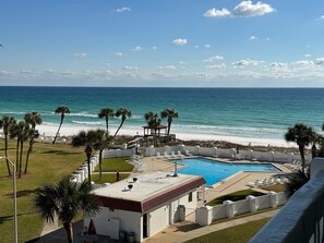 A pool area with a view of the ocean, palm trees, and a gazebo. - 451 El Matador (Fort Walton Beach)