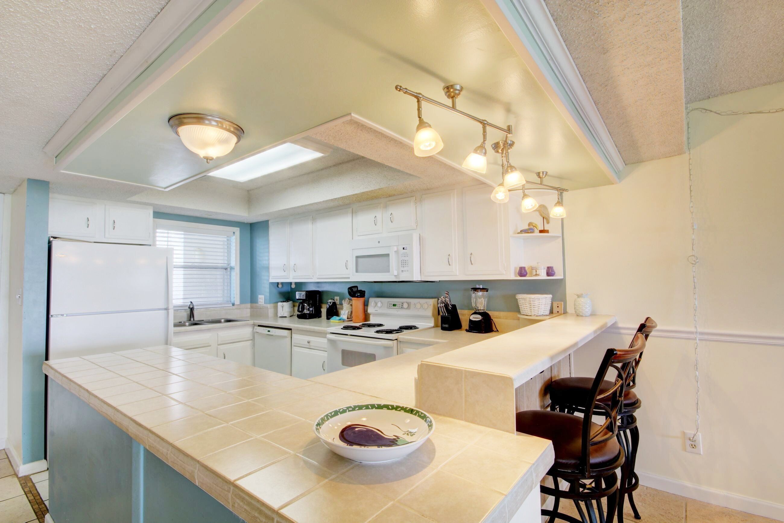 A modern kitchen with white cabinets, a large island, and pendant lighting.