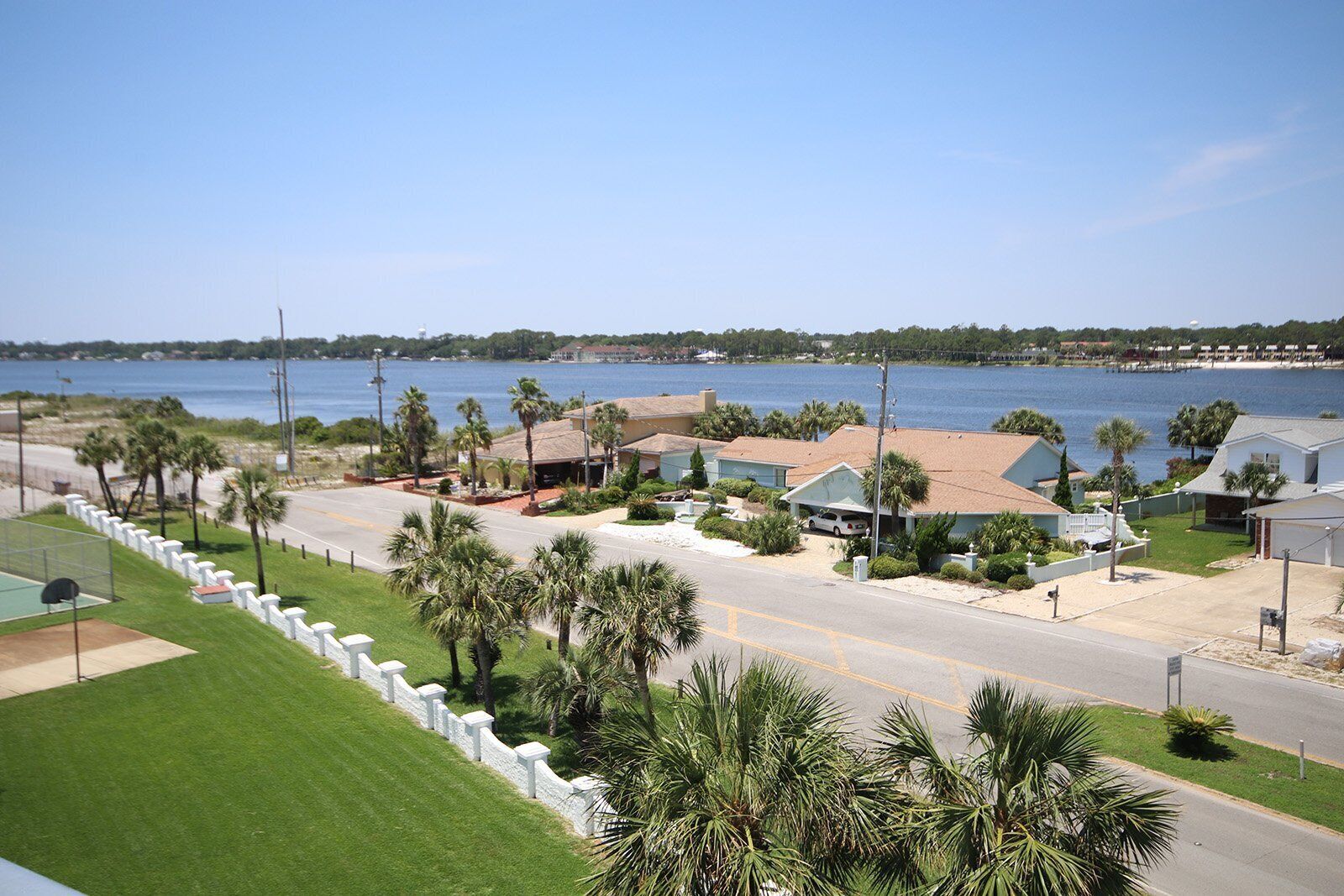 A residential area with houses, a road, and a beach in the background.