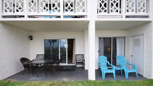 Eine überdachte Terrasse mit Tisch und Stühlen, eine Glasschiebetür und ein Balkon mit dekorativen Geländern.