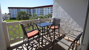 Ein Balkon mit Tisch und Stühlen, Blick auf ein Mehrfamilienhaus mit Balkonen und einem klaren Himmel.