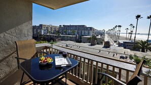A balcony with a table, chairs, and a view of the beach and buildings. - North Coast Village D204 (Oceanside)
