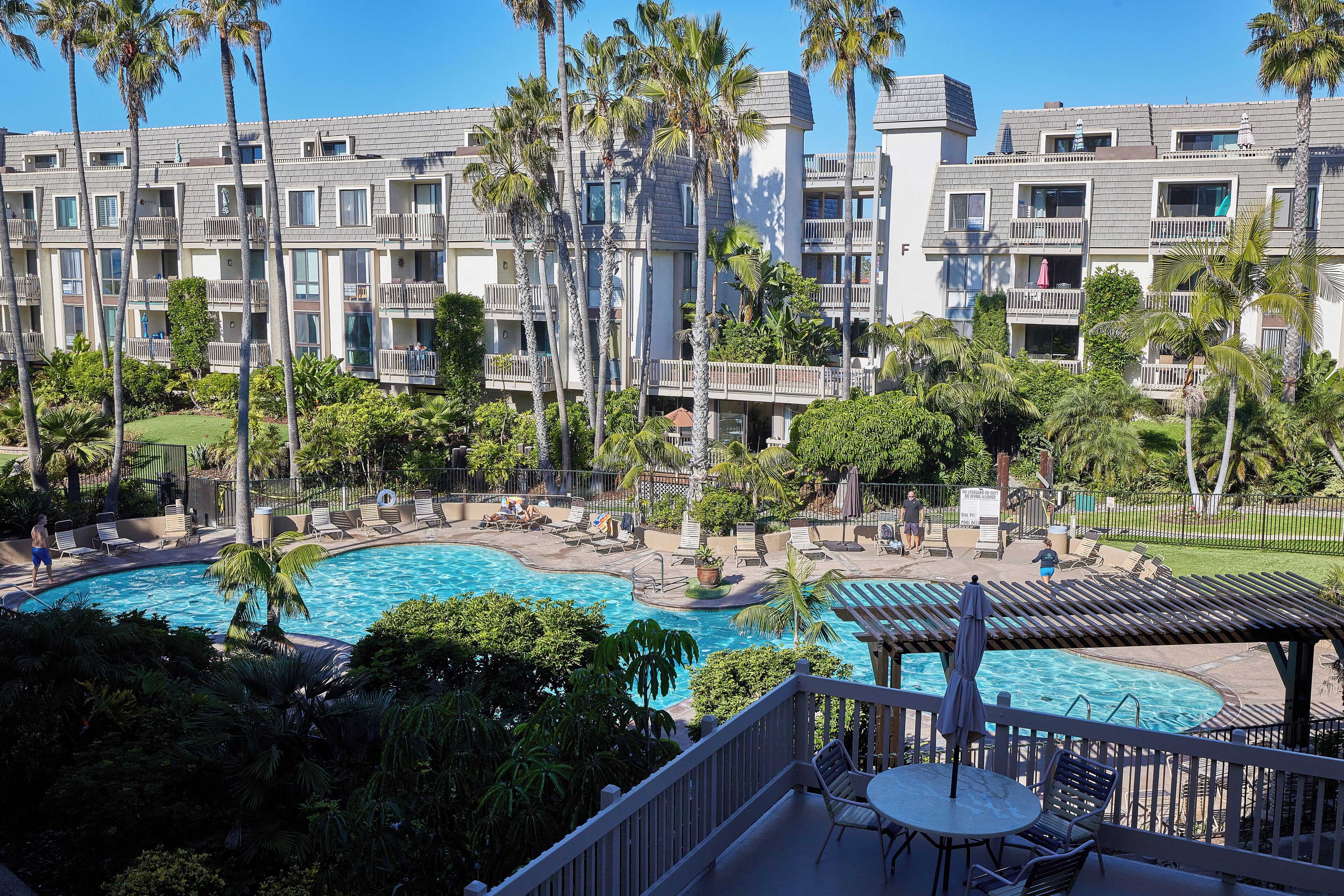 A hotel with a swimming pool surrounded by palm trees and lounge chairs.