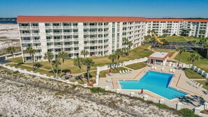 Un hotel con varios pisos, piscina y zona de playa.
