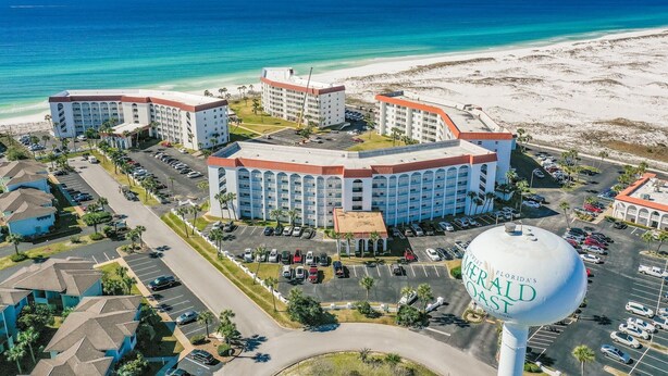 Un hotel con varias construcciones, estacionamientos y vistas a la playa.