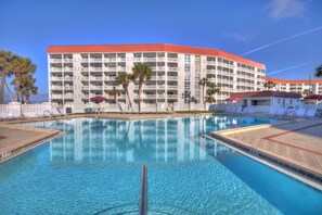 Un hôtel doté d’une piscine, de palmiers et d’un toit rouge.