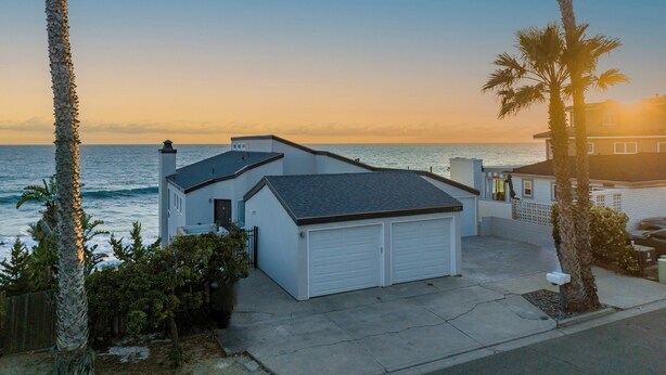 Einbungalow mit Garage, kleiner Veranda und Blick auf das Meer bei Sonnenuntergang.