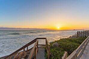A wooden pathway leading to a beach with a sunset in the background. - 1317 S Pacific - Unit A (Oceanside)