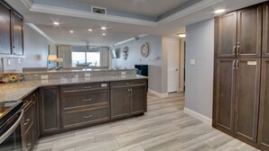 A modern kitchen with dark wood cabinets, granite countertops, and a large island. - 448 El Matador (Fort Walton Beach)