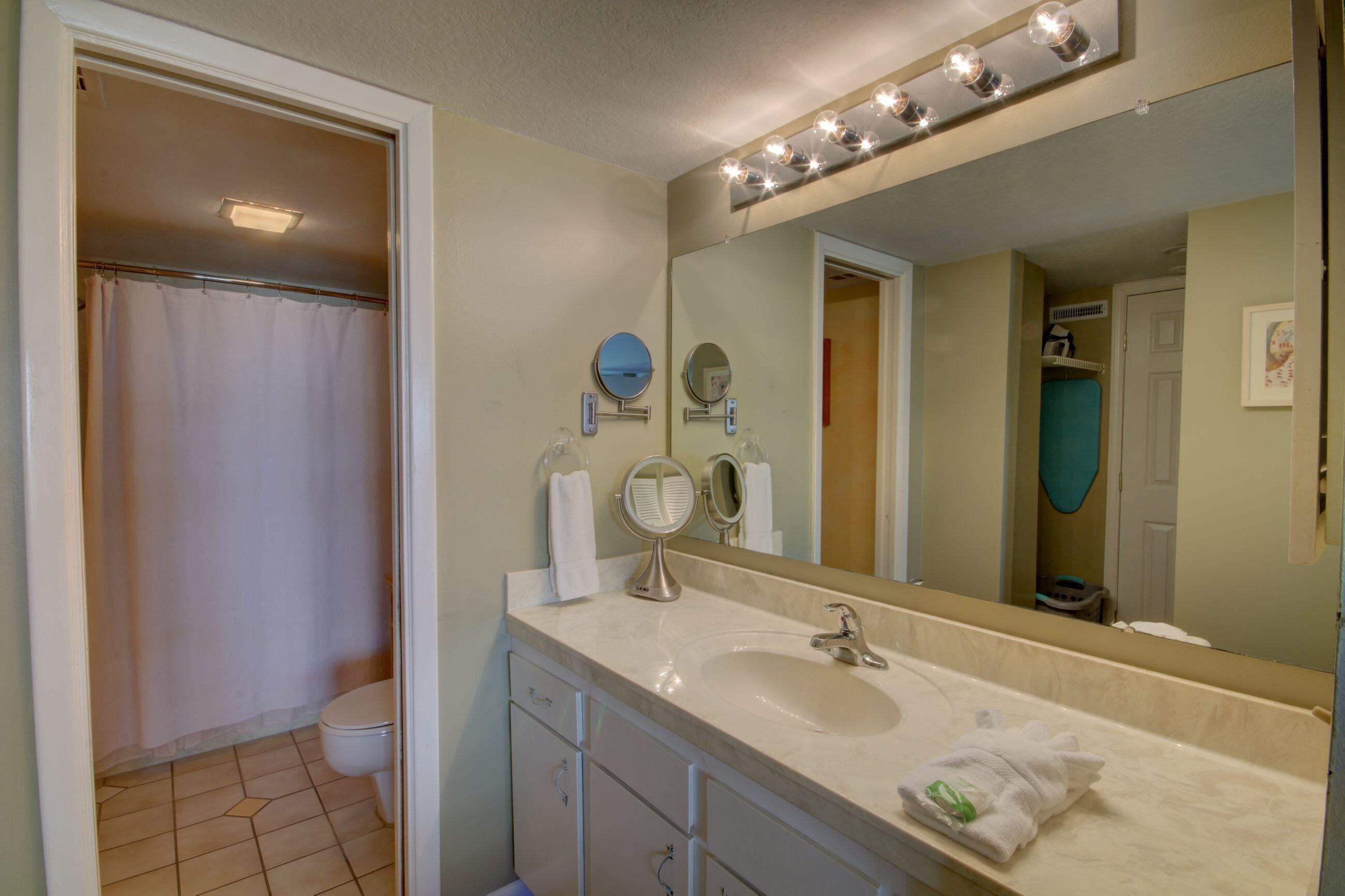 A bathroom with a sink, mirror, and shower curtain.