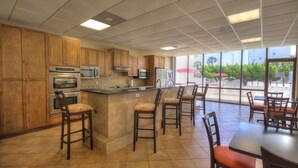 A kitchen with wooden cabinets, stainless steel appliances, and a bar area with stools. - 141 El Matador (Fort Walton Beach)