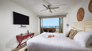 Ein Hotelzimmer mit einem großen Bett, einem Flachbildfernseher, einem Deckenventilator und Blick aufs Meer.
