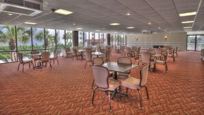 Una sala conferenze con tavoli e sedie, ampie finestre e un tappeto a motivi.