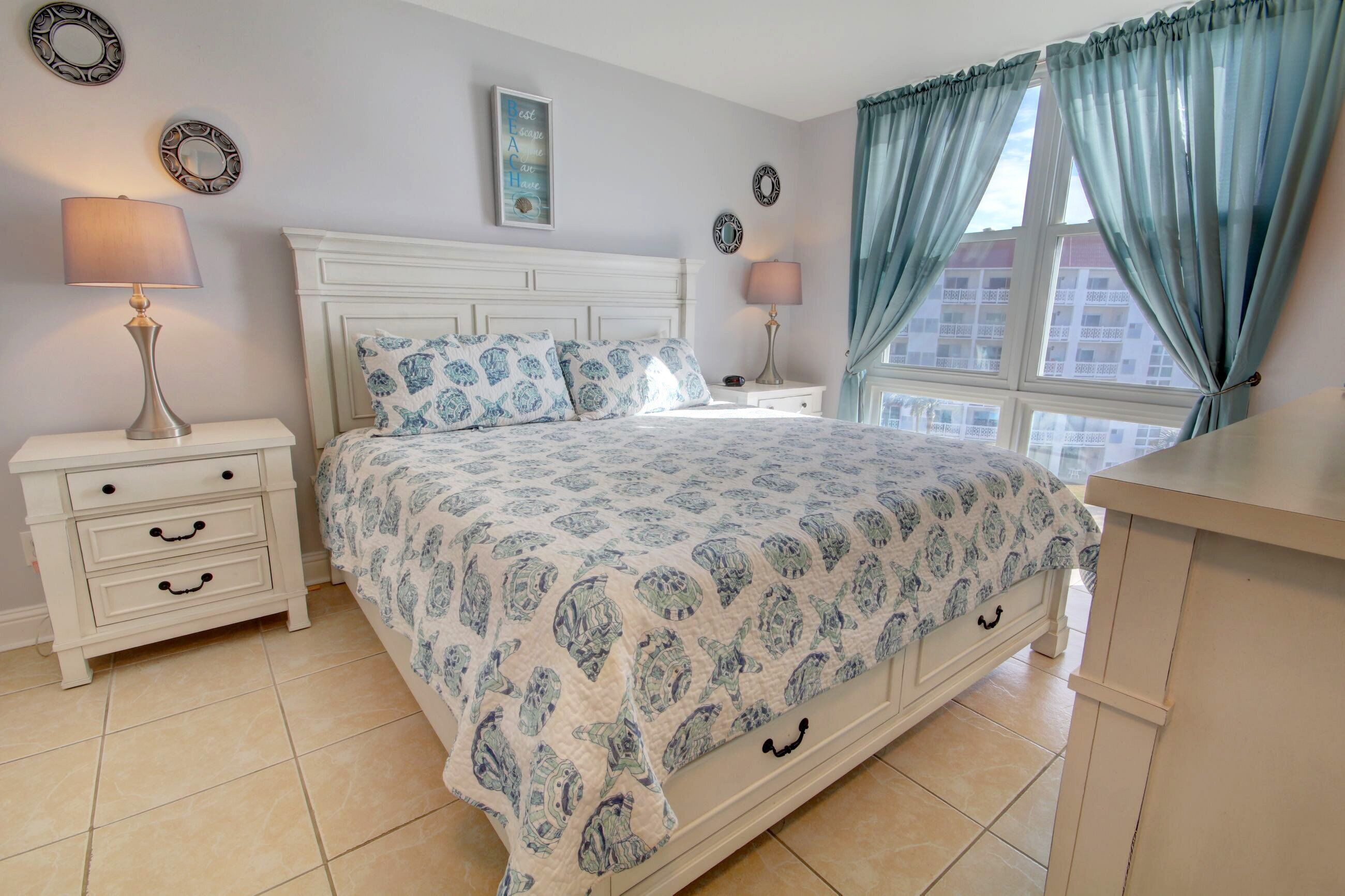 Een slaapkamer met een bed, twee nachtkastjes, een lamp en een raam met gordijnen.