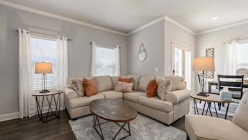A living room with a sectional sofa, two side tables with lamps, a coffee table, and a clock on the wall.