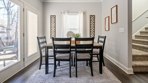 A dining area with a table and chairs, a window with curtains, and a staircase. - 2059 Pinnacle Walk Drive, Norcross (Norcross)