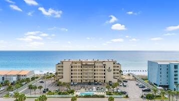 A hotel with a pool, parking lot, and ocean view.