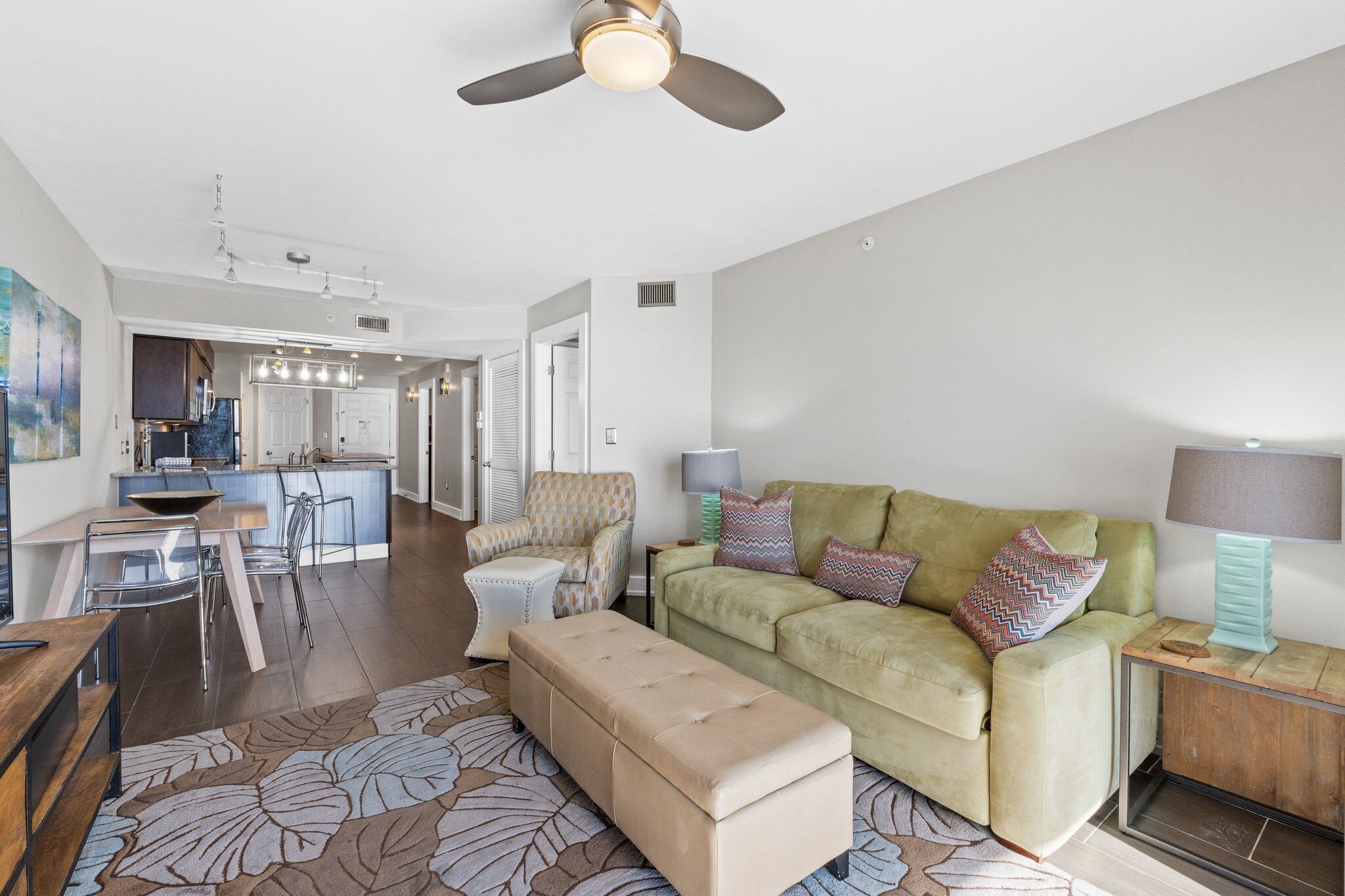 A modern living room with a green sofa, a wooden coffee table, and a ceiling fan.