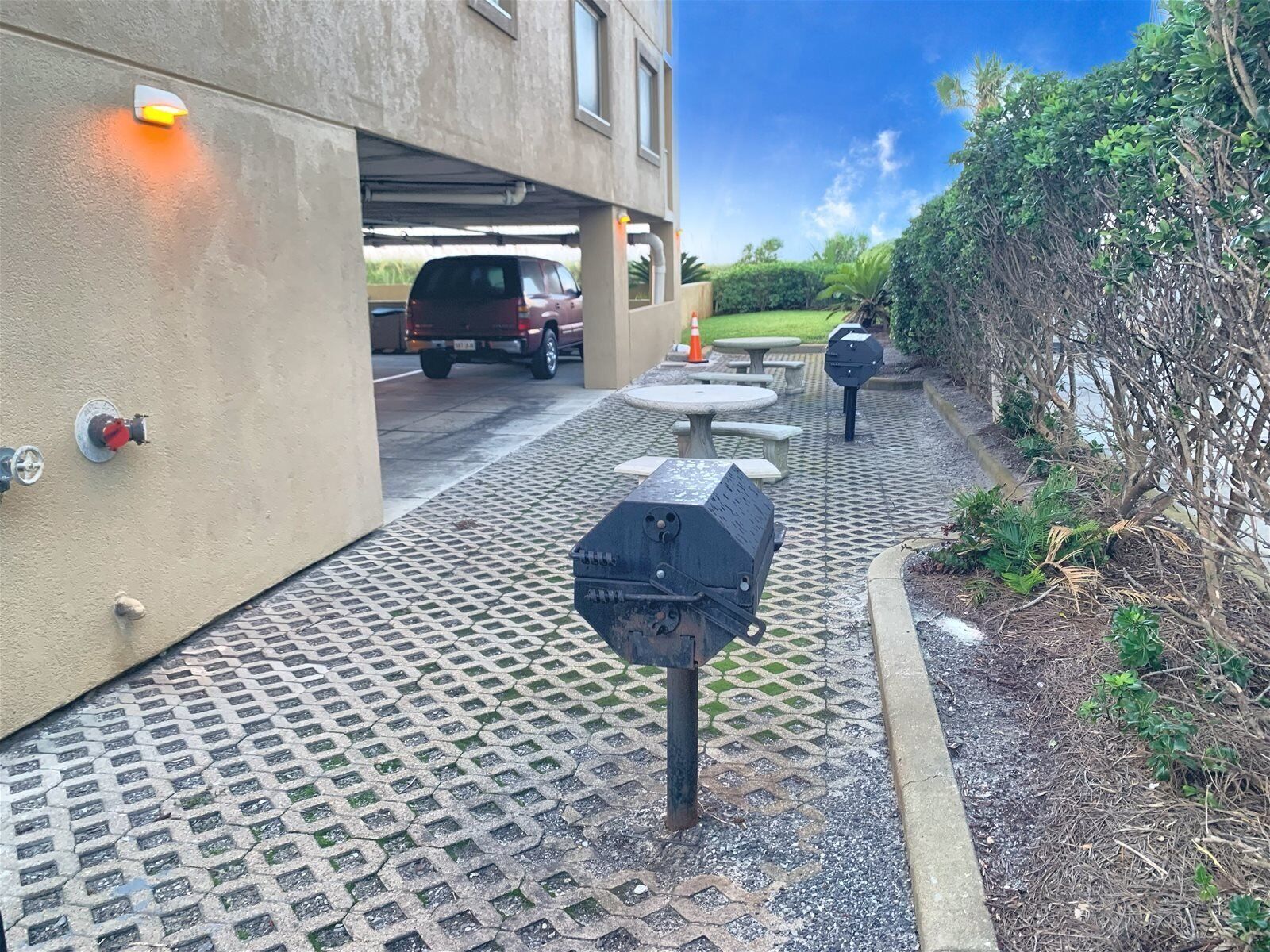 A parking area with a covered section, outdoor seating, and a vehicle parked inside.